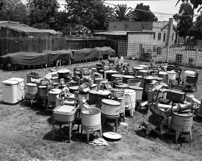 Black and white photo of dozens of retired washing machines in a yard from Jessee Appliances, Orange County, California, May 29, 1951.