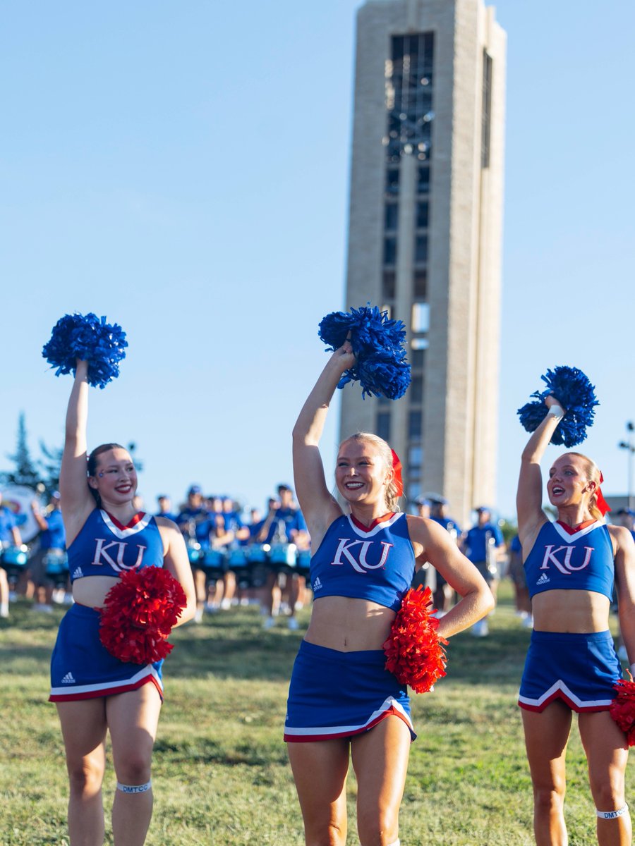 On Campanile Hill, three KU cheerleaders raise their pompoms in welcome.