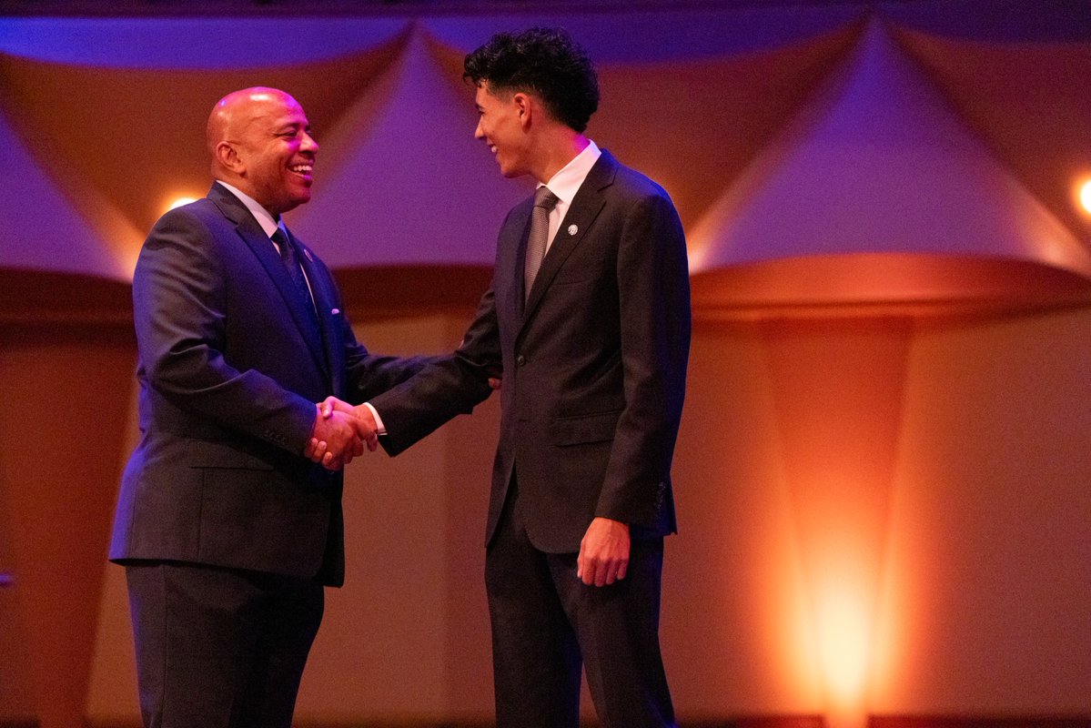 Two men shake hands on a stage
