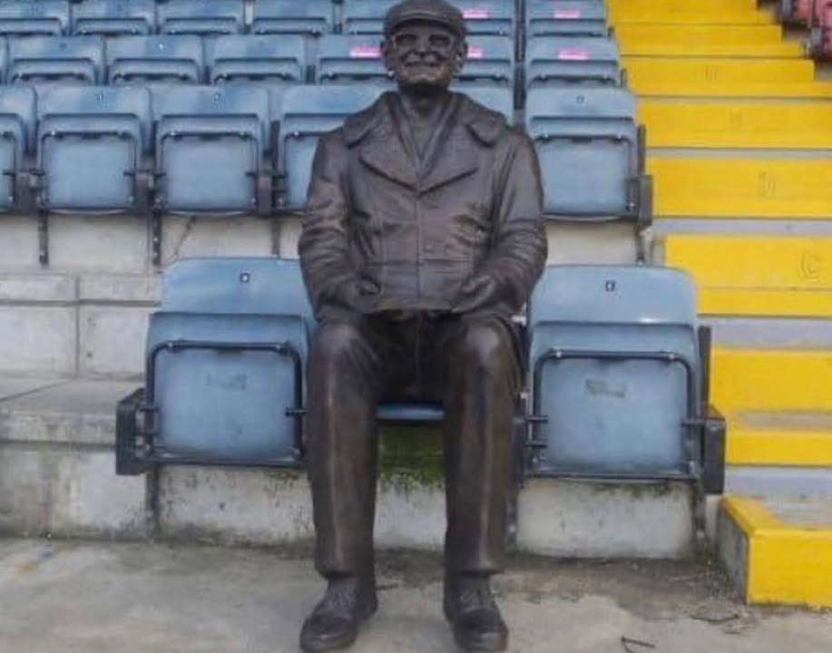 AwayDaysFB's tweet photo. David Clough was a lifelong Rochdale fan, following the club home and and away throughout his life.

When David passed away in 2020, he left a large sum of money for the club in his will. 

This statue of him was installed where he sat for home games.

Love that! ❤️ https://t.co/zeepeersEh