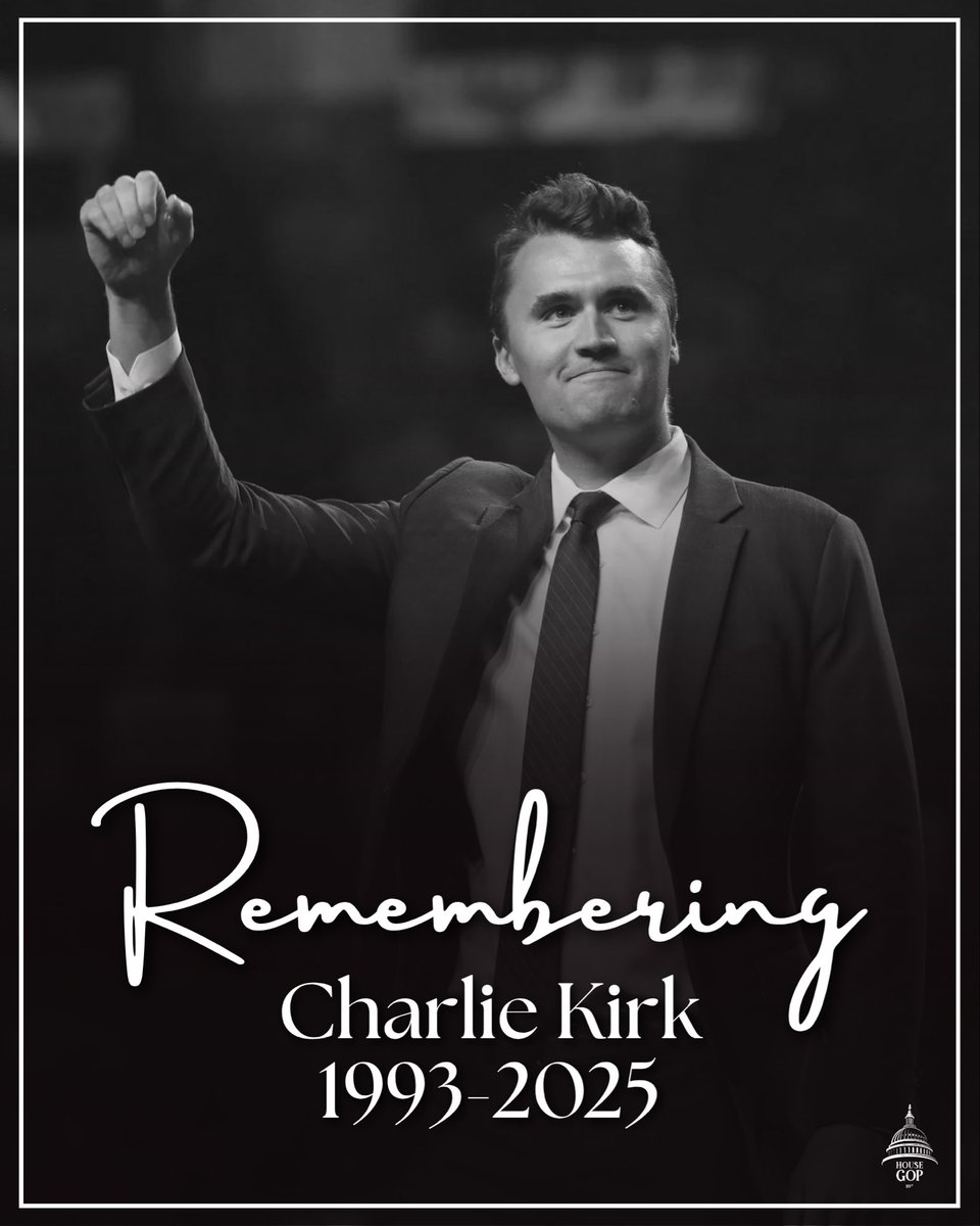 A black-and-white memorial poster featuring a man in a suit raising one fist. A thin white border frames the poster, with memorial wording near the bottom and a small logo in the lower-right corner.