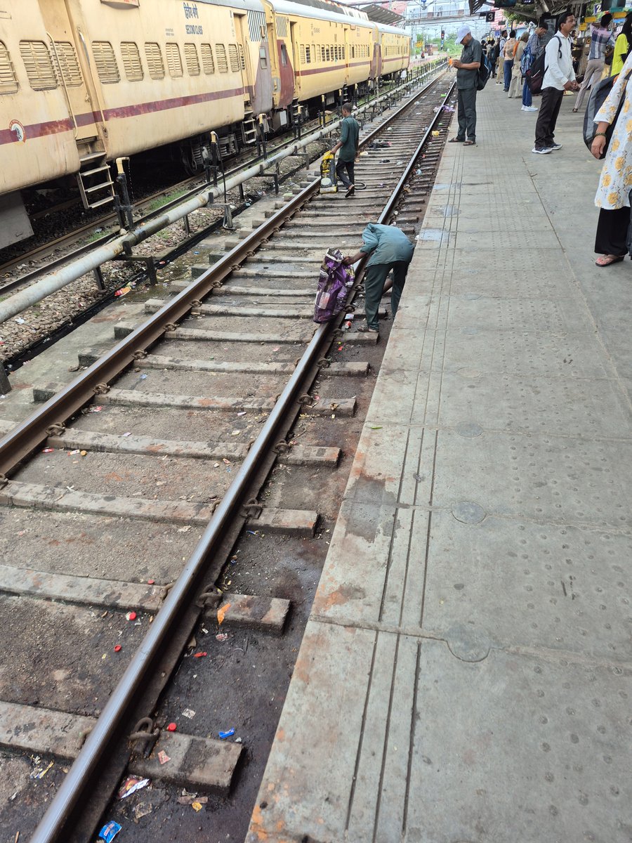 DrSharunS's tweet photo. This is an urgent call for attention to the working conditions of the cleaning staff at our railway stations.

​I clicked these pictures during my recent travel. Though the cleaniness of our railway stations have significantly improved comapred to earlier standards, you can see cleaners picking up garbage from the tracks with their bare hands. This is a severe health hazard and completely unacceptable for their well-being.

They are directly exposed to:
​⚠️ Pathogens from human waste and decomposing refuse, leading to diseases like Tetanus, Hepatitis, and Typhoid.
⚠️ Cuts and punctures from sharp objects like glass, syringes, and metal, which can cause serious infections.
⚠️ Direct contact with toxic chemicals and industrial pollutants present on the tracks.

I request ​Indian Railways to implement standard safety protocols by providing proper personal protective equipment (PPE) to all track cleaners. This must include, at a minimum:
✅ Sturdy, cut-resistant gloves to protect hands.
✅ Durable gum boots (industrial boots) to protect feet from sharps and contaminated water.

​I urge the authorities to address this matter. These frontline workers deserve dignity and safety in their vital roles.
​@RailMinIndia @AshwiniVaishnaw