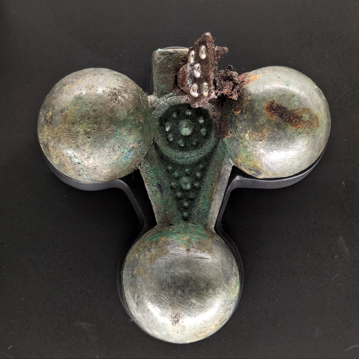 sakitama_museum's tweet photo. もうすぐシルバーウィーク！
シルバー（銀）が使われた国宝（稲荷山古墳出土品）をさがそう！
馬を飾る銅製の鈴杏葉（すずぎょうよう）です。革紐に留めるための鉄の金具に丸い鋲が５つ見えます。鋲の頭には銀の薄板を被せて銀色に飾っています。おしゃれで凝った作りですね。展示中！ https://t.co/1wI0lpJXjB