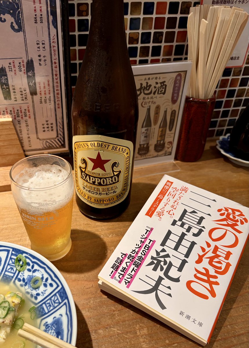 kinyachan's tweet photo. #明石 で週末の独酌🍶
かき揚げが、20分待ってもこないので、#愛の渇き 〈 #三島由紀夫 〉を読む。初読は1983年19歳。なぜ読んだかは失念。当時の読書ノートの一文は覚えている。「純文学はなんでもありやな、狡いな」。何を偉そうに（苦笑）。かき揚げを待ちながら40年以上前の自分と、しばし一献。 https://t.co/yFOLJ39wtI