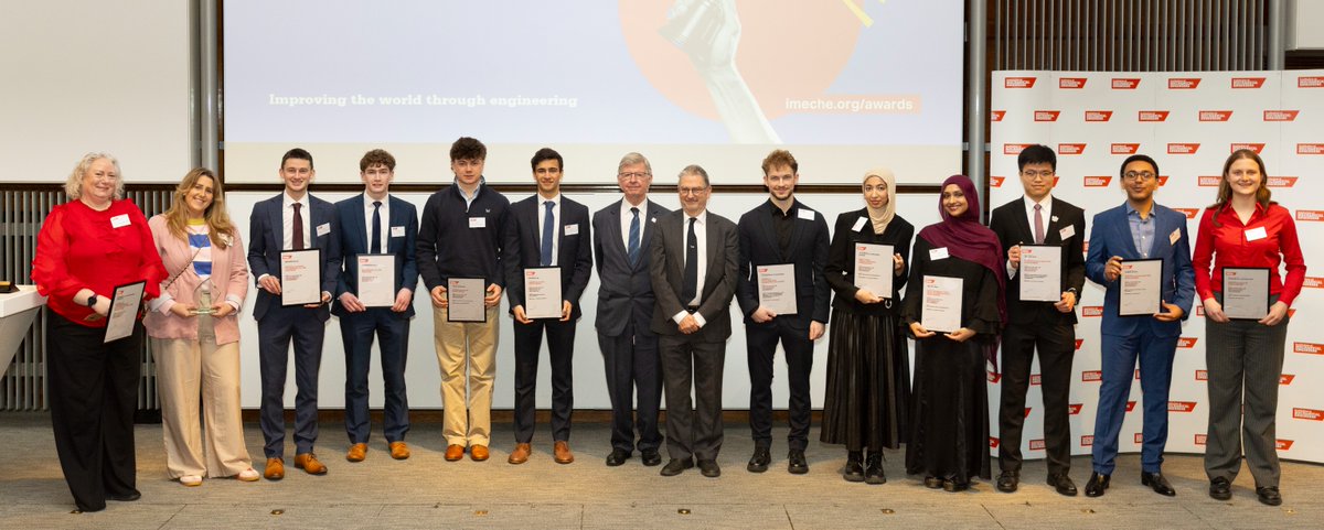Group of young adults and officials standing in a row holding certificates at an award ceremony indoors.