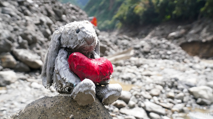 shanghaidaily's tweet photo. At the Gyirong mudslide search site, a rabbit plushie caked in mud, still holding a bright red heart, was found among the debris. A firefighter gently placed it on a high rock before turning back to continue the search. https://t.co/4o0ve9pNAA