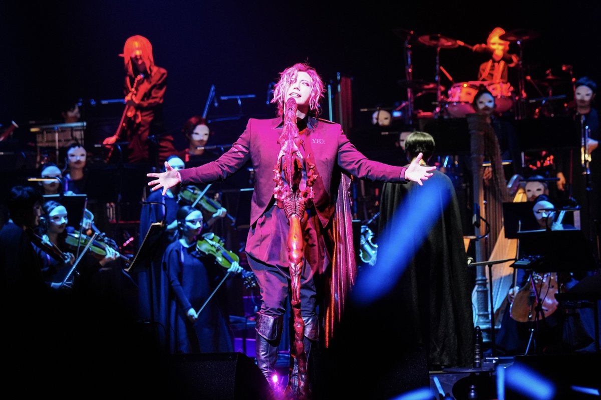 GACKT's tweet photo. 『ボクをまともな人間だと思ってるのか？』

このレポートを読んで、
改めて思ったのだが…。

【魔王シンフォニー】を
「クラシックコンサート」だと思って来た人には申し訳ない。

客は叫ぶ。
指揮者はタクトを振り乱し、
オーケストラは狂い出し、
見ているみんなが、
気づけば儀式に参加している。

どう考えても、
品行方正なクラシックではない。

だが、
最初からそんなものを
作る気は1ミリもない。

静かに座って、
上品に音楽を聴いて、
拍手して帰る。

そんな予定調和なら、
ボクじゃなくても作れる。

ボクが欲しかったのは、
演者と客席の境界が壊れ、
オーケストラとバンドの境界も壊れ、
最後には、

【自分が何を観に来たのかすら分からなくなる世界】

それだよ、それ。

いや、
それが魔王シンフォニー。

「魔王シンフォニーって、
結局なんだったんですか？」

そう聞かれたら、
こう答える。

自分で考えろ。

ボクもよく分からん。
だから面白い。

予定調和に安心する人は、
わざわざ来る必要はない。

ボクはいつも、
色んなものを必死に組み立てて、
完成しそうになると壊したくなる。

で、
また組み立てる。

そう、
破綻してる。

まあ、
破綻してないヤツが
【魔王シンフォニー】なんて名前を付けるわけないだろ？