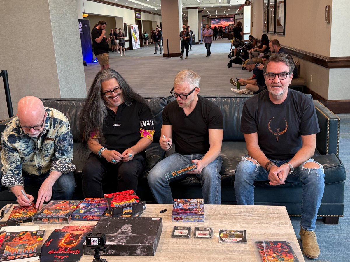 romero's tweet photo. Some pics from QuakeCon 2026. The founders with Miss Donna, me and @AndrewHulshult, me and Hugo Martin, me @ThatTomHall @ID_AA_Carmack and @ACarmackArtist signing a bunch of our games. https://t.co/4FodGELwS8