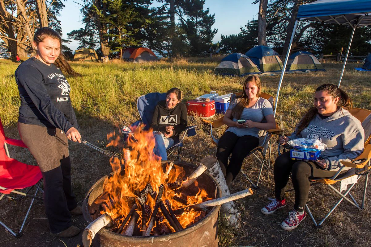 Young women roasting s'mores over a campfire at New Brighton State Beach. 