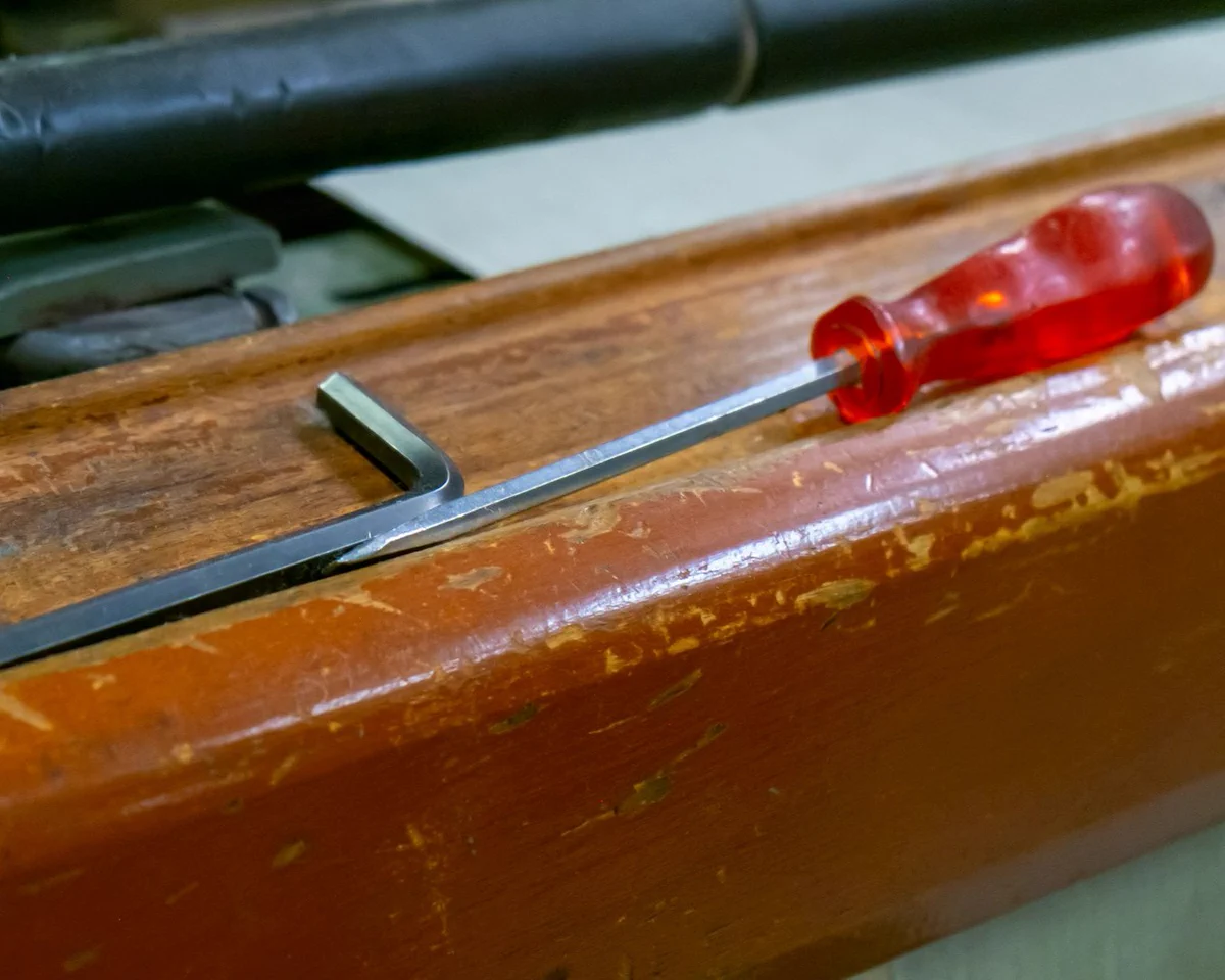 A screwdriver with a translucent red handle rests on a worn wooden surface.