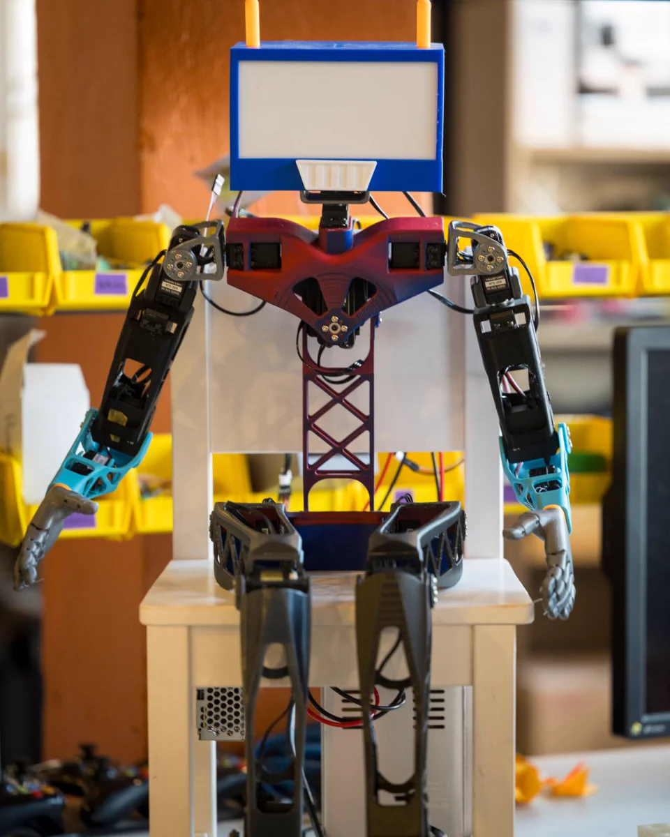 A colorful humanoid robot stands in a research lab.
