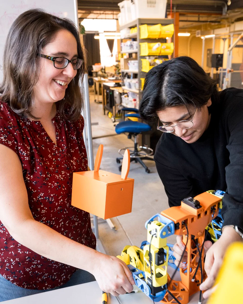 Naomi Fitter, Ph.D., and a student examine a humanoid robot in a lab.