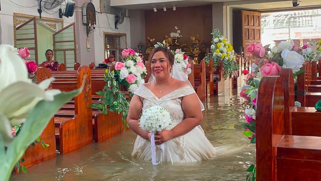 inquirerdotnet's tweet photo. TULOY ANG KASAL 💒

LOOK: A couple pushed through with their wedding ceremony in waist-deep floodwaters at San Juan Bautista Parish in Hagonoy, Bulacan, on Tuesday, September 1.

According to the parish, the couple chose not to reschedule despite flood advisories. The bride had her wedding gown shortened to navigate the flooded aisle, while the church used a portable speaker due to a power outage. | 📷: Ang Tinig - St. John the Baptist Parish Hagonoy, Bulacan via Danna Engracia, https://t.co/E0yNJSWpUY trainee