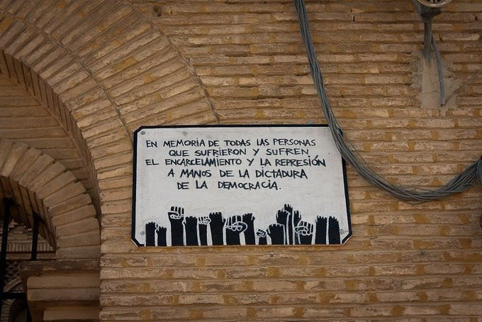 outsidersesp's tweet photo. En recuerdo de Kike Mur.

En la madrugada del 1 de septiembre de 1997 unos gritos despiertan a los internos de la cárcel de Torrero en Zaragoza. Quedaba apenas un mes para que el insumiso Kike Mur cumpliera su condena de dos años cuatro meses y un día. Aunque hacía tiempo le correspondía la condicional, la actitud de Kike a no colaborar con las autoridades de la prisión, como parte de las luchas llevadas por los internos insumisos del centro, había repercutido en su condena, especialmente restrictiva. Incluso, Kike era obligado en tercer grado a pasar por prisión a la hora de la comida y a dormir, cuando el resto de internos tan solo tenía que pernoctar en su celda.

Aquella madrugada Kike apareció inconsciente en su celda. Tuvieron que ser los propios presos los que iniciaran las primeras labores de auxilio. Los funcionarios se mostraron especialmente pasivos y el médico de la prisión no apareció en escena hasta una hora después. Cuando al fin llegó una UVI móvil para atenderlo los carceleros la detuvieron para tomar las huellas a Kike, lo que desató la furia de los demás presos. Kike ingresó ya cadáver a su llegada al hospital.
El informe oficial decretó la ingesta de arsénico como causa de la muerte, pero los demás presos siempre rechazaron la idea del suicidio. En el 98 la causa quedó archivada negando cualquier negligencia por parte de los carceleros. Las manifestaciones de protesta y solidaridad con la causa de Kike se repitieron durante meses por toda la península.

Ese mismo año, 1997, en febrero se suicidaba antes de volver a prisión tras disfrutar de un permiso el también insumiso Unai Salanueva. También, una joven, Virginia, muere arrollada por un vehículo durante una protesta de apoyo a los presos insumisos en la puerta de la cárcel de Topas. Ella permaneció más de 20 minutos tendida en el suelo antes de morir ante la indiferencia del personal de la cárcel. En los tres casos la indiferencia de los medios fue mayúscula.