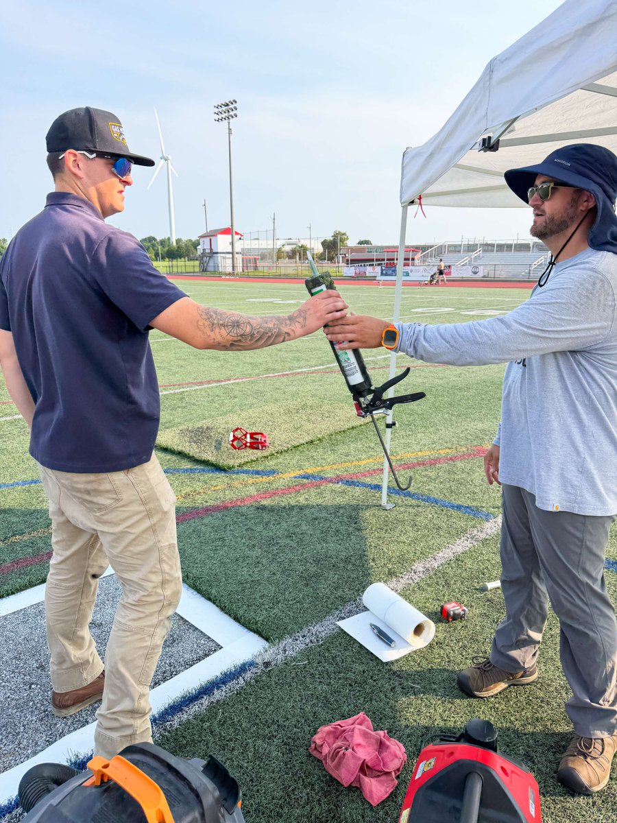 TurfOptiX's tweet photo. Passing the torch? More like, passing the turf adhesive! 🏃‍♂️‍➡️

Seamless repairs take teamwork, communication, and making sure the guy holding the glue gun knows what he's doing! #TurfRepair #Teamwork #TurfOptix #SyntheticTurf #GlueGun https://t.co/Of9g34aeDd