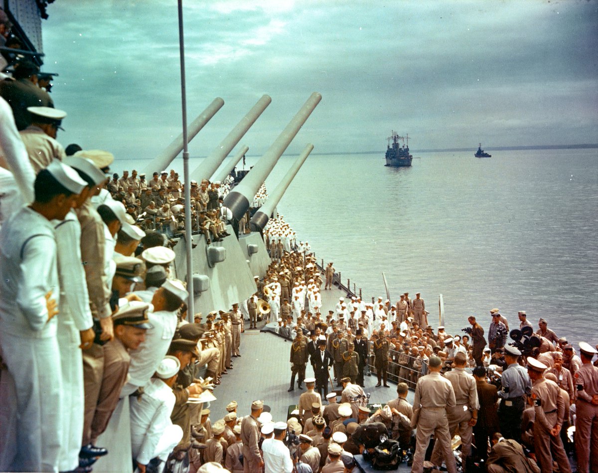 hwtnv's tweet photo. 81年前の今日。1945年9月2日，戦艦ミズーリの艦上で，日本の降伏文書に署名するコンラッド・ヘルフリッヒ提督。隣にはマッカーサー元帥が立っている。カラーで撮影された写真。 https://t.co/GB6FuenQFM