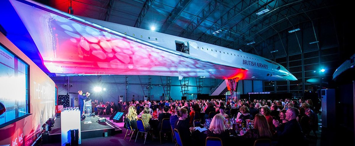 Large audience listening to a speaker under the wing of a British Airways Concorde aircraft.