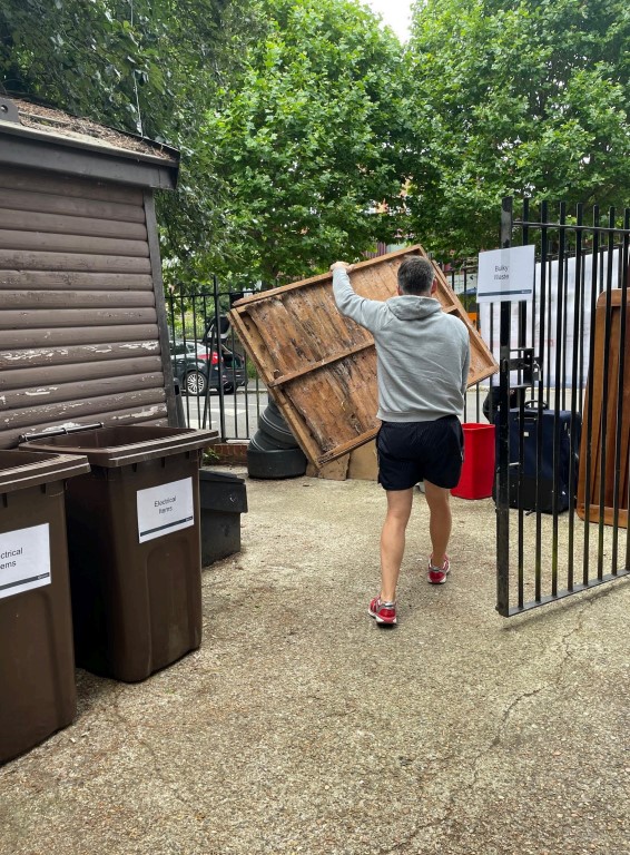 Image shows a resident depositing a wooden panel in the bulky waste section at a previous skip event