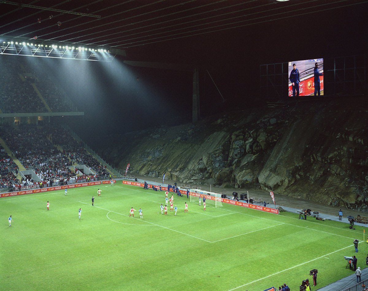 RandomFootbaw's tweet photo. 🇵🇹 SC Braga play their home games in a stadium carved into a granite quarry.

The Estádio Municipal de Braga was built ahead of Euro 2004 on the site of the Monte do Castro quarry.

Instead of enclosing the pitch with four stands, architect Eduardo Souto de Moura designed just two.

They face each other along the touchlines.

Behind one goal is the exposed rock face of the quarry.

Behind the other, the stadium simply opens out towards the surrounding landscape.

Even the roof is unusual, suspended between the two stands by cables rather than supported around a conventional stadium bowl.

The ground opened in 2003 and became one of the venues for Euro 2004.

Locally, it is appropriately known as A Pedreira.

The Quarry.

There really aren’t many places in football that look like this.

#Braga
