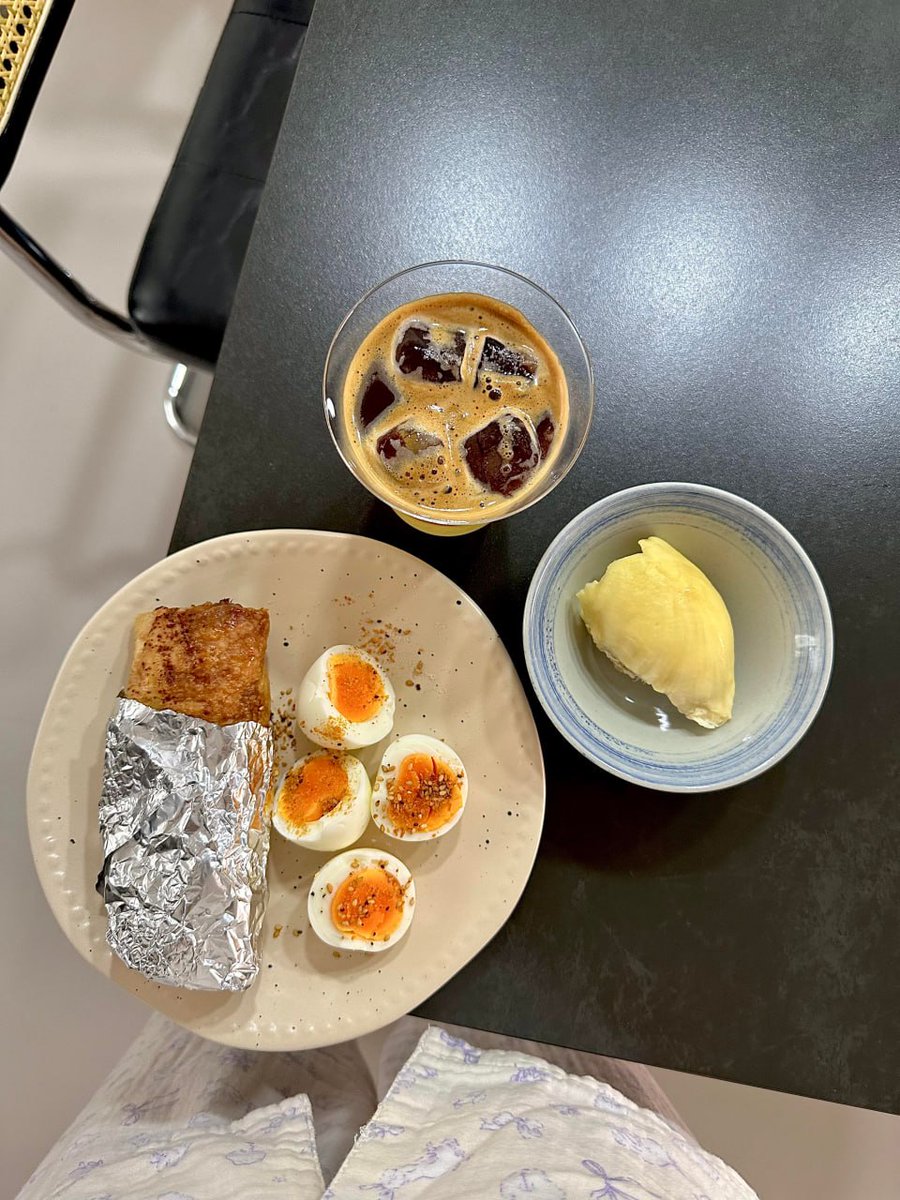 Keepsmilingqwer's tweet photo. Los Angeles mornings are never in a hurry.The sunlight hasn’t fully draped the city yet, but the table already has its own rhythm.Four jammy eggs rest on a pale beige plate, the yolks just set into a soft orange. Sesame seeds and a pinch of chili powder fall lightly over them, like tiny sparks of light on an ordinary day.Inside the foil is a freshly cooked breakfast roll, its exterior golden and faintly crisp, still holding its warmth.Beside it, a small bowl of ripe, soft durian — a little indulgence for the morning: rich, direct, https://t.co/WLtPECD9xK the glass, a layered iced coffee: bright citrus below, deep coffee above. The ice slowly sinks. The flavor shifts as it melts, much like the weather in this city — changeable, yet always with its own layers.This isn’t a carefully plated restaurant brunch. It’s just a meal made at home, casually. No filter. No rush. Just eggs cooked to the right point, coffee poured to look a little nicer, fruit placed in a favorite small bowl.Turns out an LA breakfast can be this quiet.Right here in your own kitchen, at your own pace, slowly opening a new day.