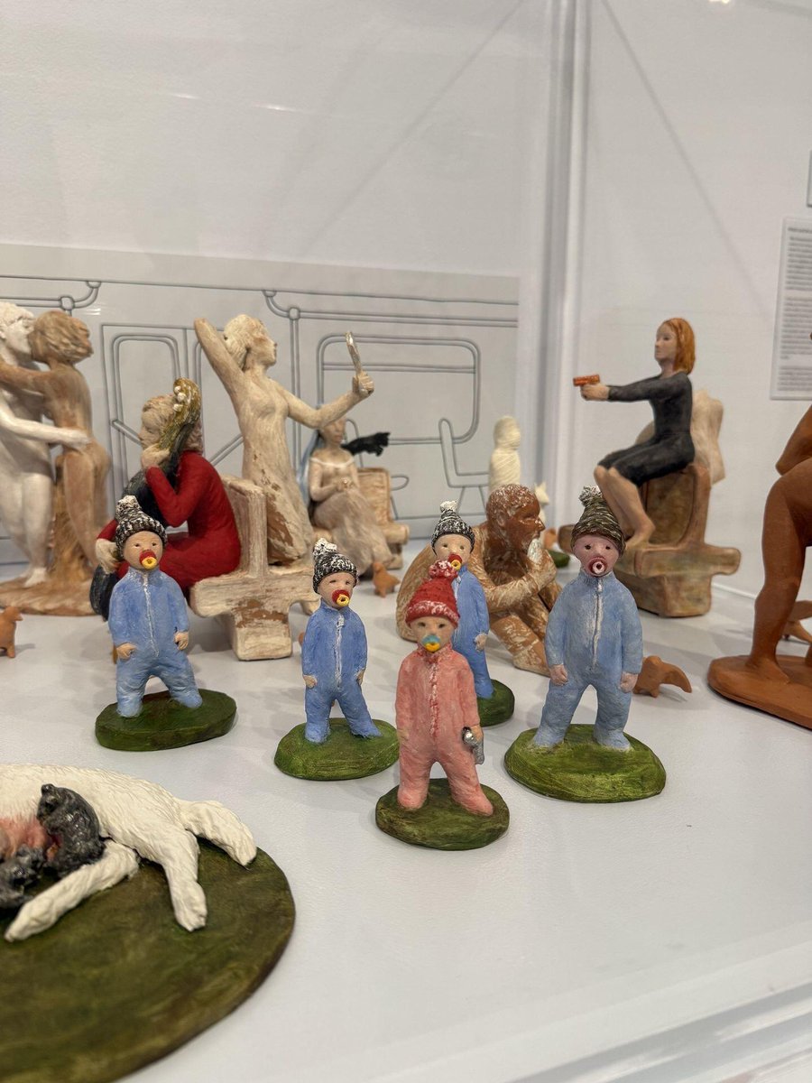 upbapRina's tweet photo. Little clay figures with pacifiers and beanies standing on tiny green bases. Weird and funny sculptures all lined up in the display. Just a quirky art find that makes you stop and look twice https://t.co/t1aenFGQsc
