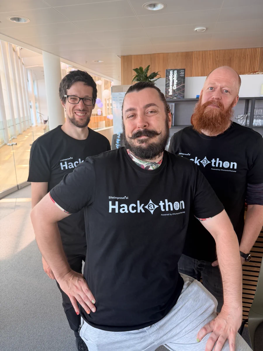 Three Copenhagen Siteimprovers pose close together in their Siteimprove.ai Hackathon 2026 shirts.