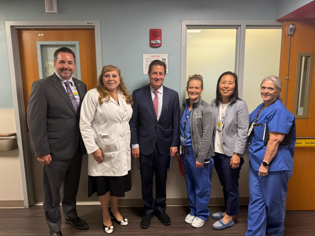 Dean Gladwin on the OB/GYN floor with physicians and nurses smiling at the camera.