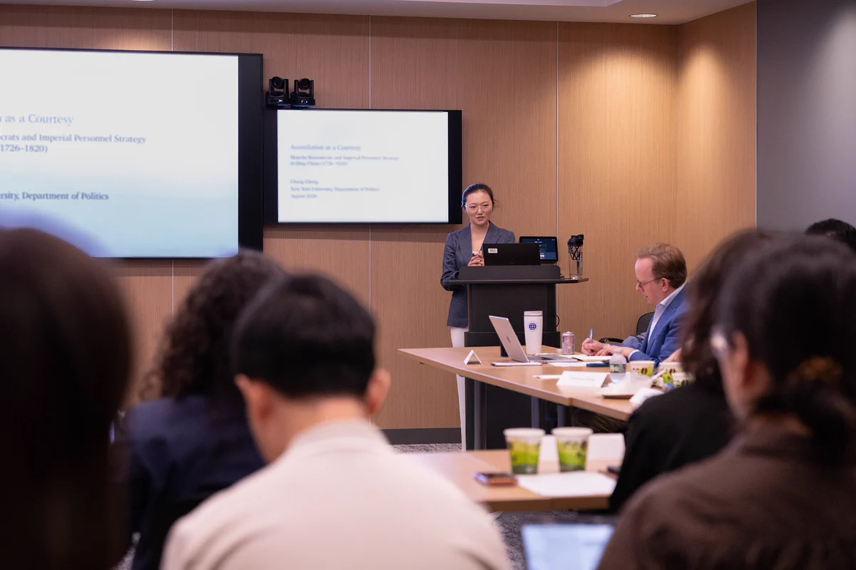 A person is giving a presentation at the front of a room full of people.