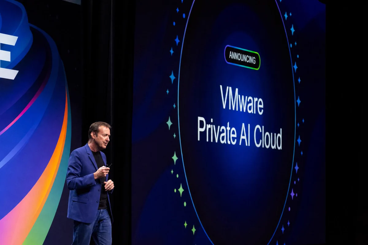 Paul Turner speaking on stage near a presentation screen that displays the text "Announcing VMware Private AI Cloud." The background features colorful graphic designs.