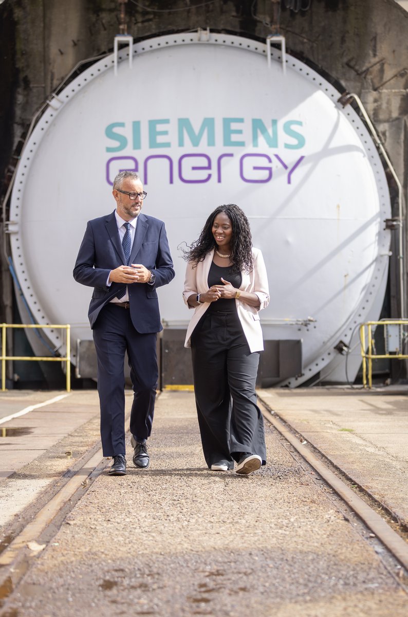 Miattah Fahnbulleh walking with an executive in front of a large Siemens Energy machine.