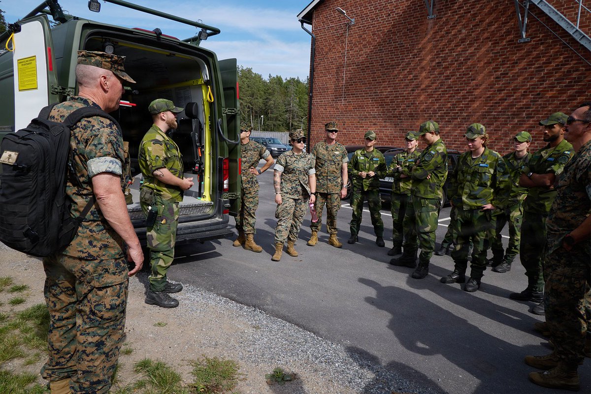 U.S. Navy corpsmen and Swedish service members gather beside a military ambulance during a medical exchange.