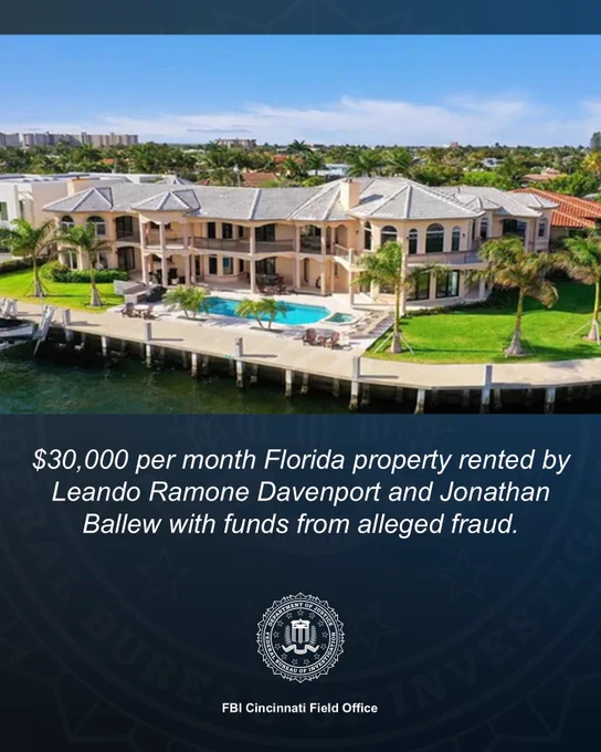 Large waterfront Florida mansion with a pool and dock, surrounded by palm trees under a clear blue sky.
