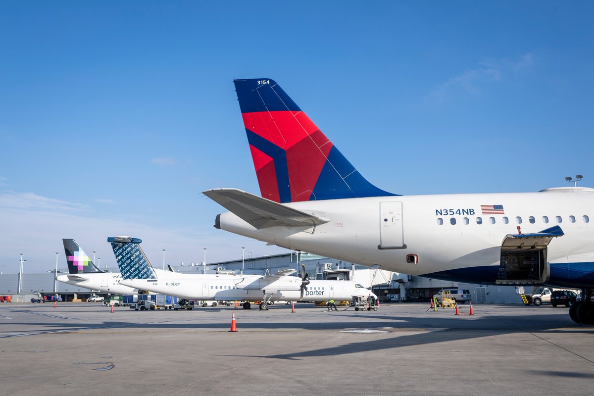 A Delta Air Lines aircraft parked at Midway International Airport, with Porter Airlines and Volaris planes visible in the background under a clear blue sky.