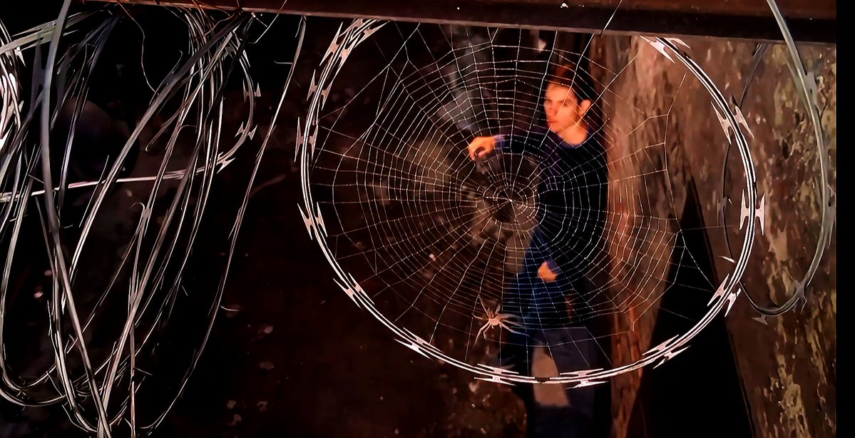 jus_jerryy's tweet photo. Look closely at how Sam Raimi framed Tobey Maguire behind the razor wire. This isn't just a cool transition, unlike modern superhero films that rely entirely on CGI environments, this entire scene was shot on a real alleyway set, making his discovery feel raw and biological. https://t.co/hHLYC1LcJd