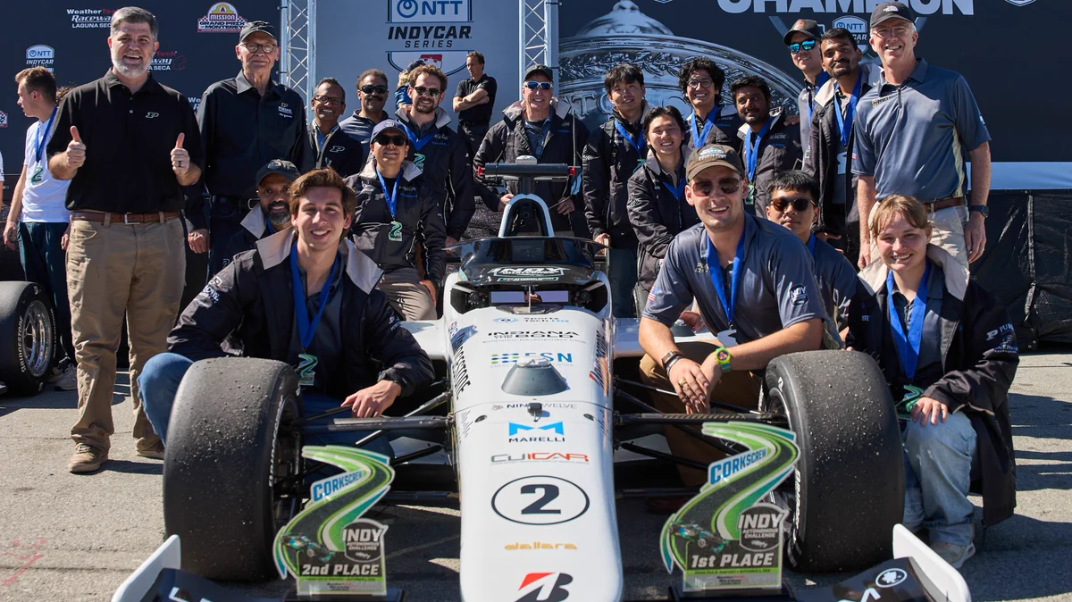 Purdue AI Racing team poses with its autonomous racecar and its Time Trials and Passing Competition trophies.