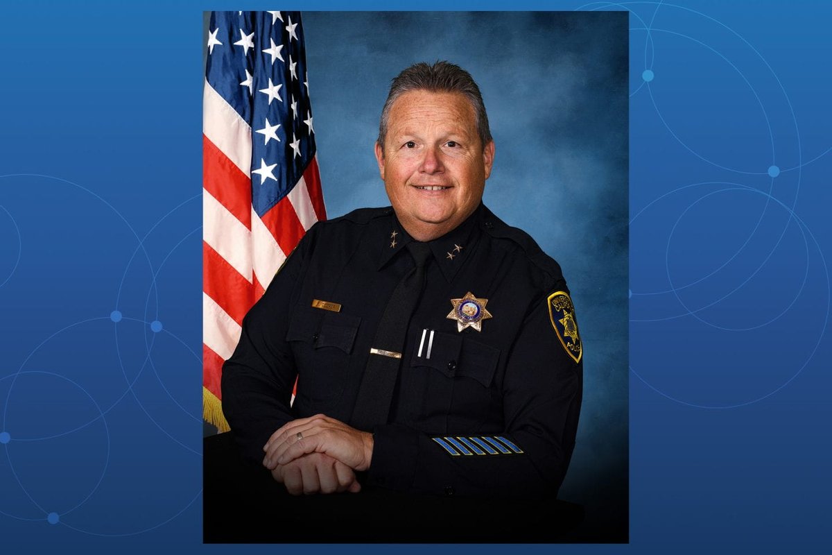 UC Irvine police chief Paul Cooper shown wearing a police uniform with an American flag visible in the background.