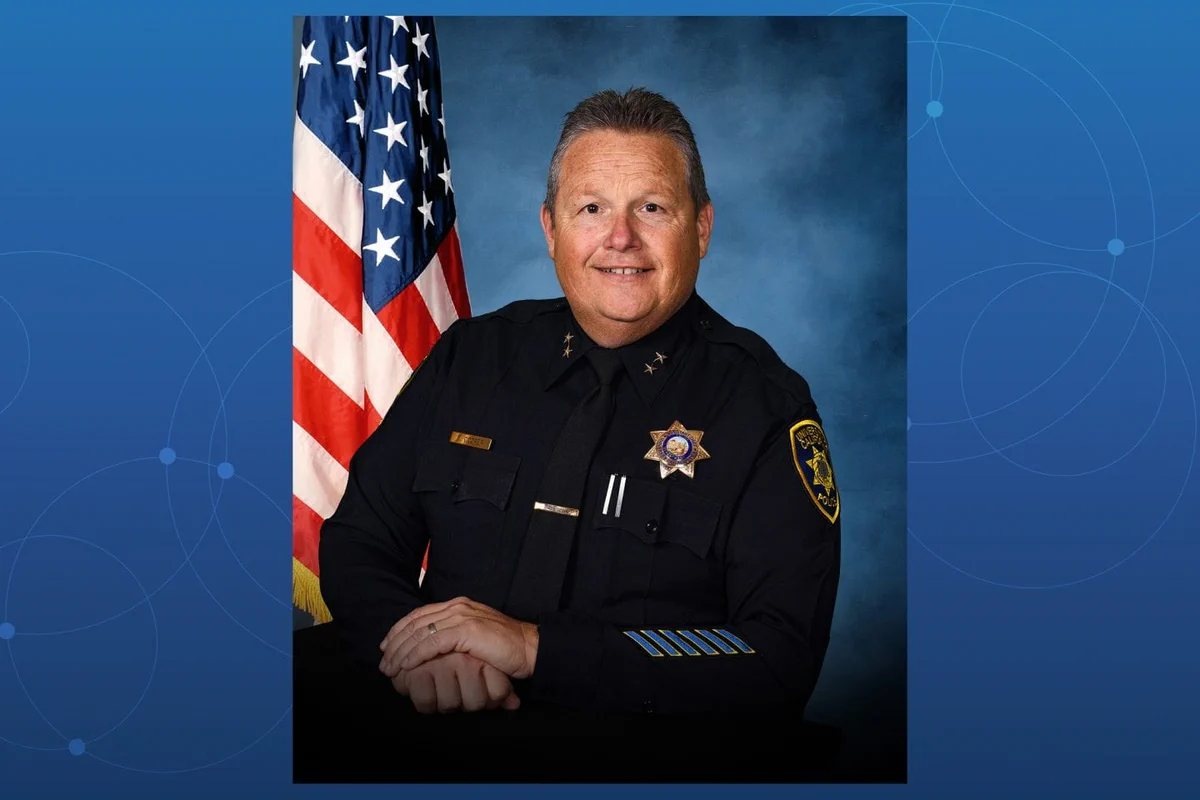 UC Irvine police chief Paul Cooper shown wearing a police uniform with an American flag visible in the background.