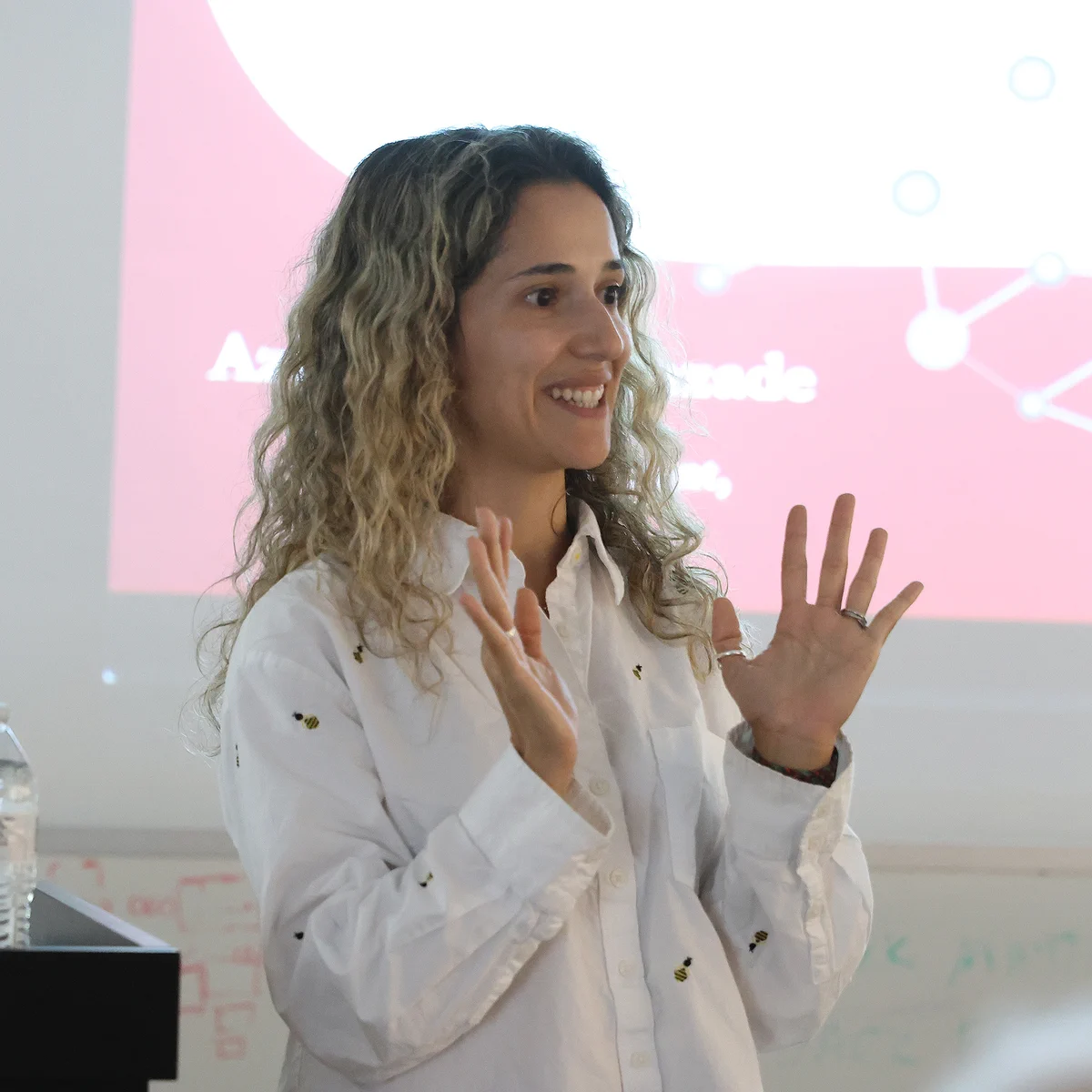 Prof. Aziza Suleymanzade, from Berkeley Physics, delivering a presentation at the UC Berkeley Space Sciences Laboratory standing in front of a projected slideshow.