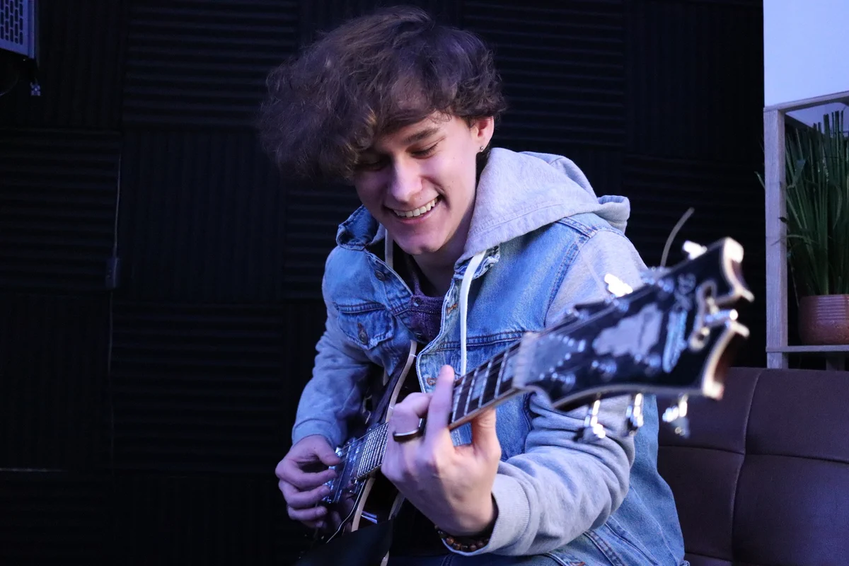 A person smiling playing the guitar 