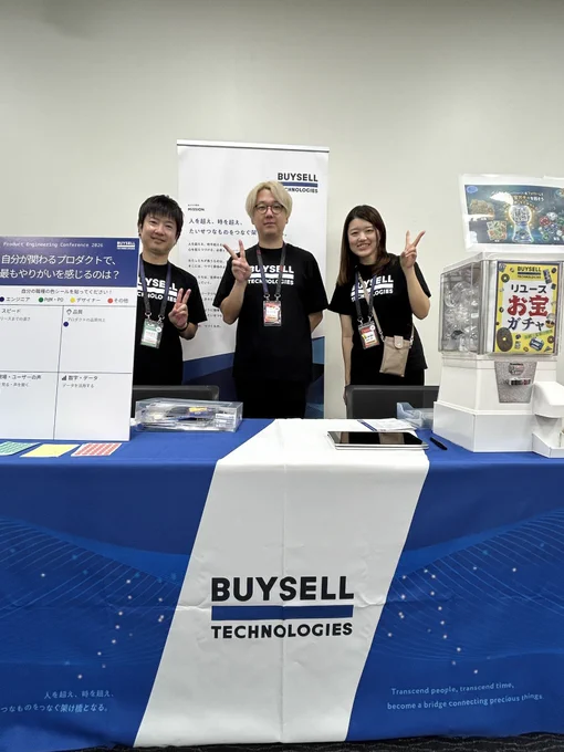 BuySell Technologiesのロゴが入った企業ブースで3名の男女がピースサインをしながら写真に写っている