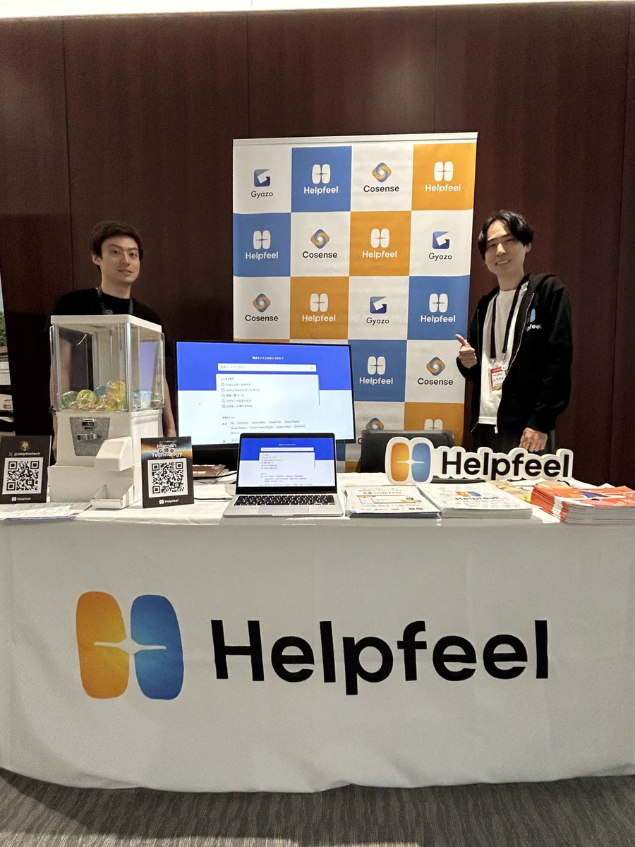 Helpfeelと書かれたテーブルクロスがかかった企業ブースの写真
2名の男性がにこやかに写真に写っている