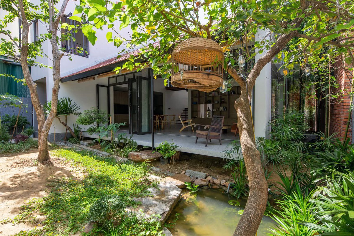shavnyuyngah's tweet photo. The Tiamo House sits on a busy street in Hà Tĩnh, Vietnam, built to shut that street out without shutting the family off from nature.

Dom Architect Studio split the 130 square meter plot into layers instead of one solid block. The old garage became a front porch, a small garden and aquarium sit just beyond it, and the living spaces open onto long verandas that pull air straight through the house.

The client’s brief also had to answer to Hà Tĩnh’s flooding. The garage sits low, the main house sits higher, and a short run of steps between them keeps the living space dry in the rainy season without cutting the visual line between inside and out.

Bare brick, grindstone, raw wood, and unfinished concrete carry the whole material palette, chosen because the owner, a photographer, wanted a house that looked like the materials it was actually made of.

A house that hides from the road, floods with the season instead of fighting it, and still leaves nothing hidden about what it’s built from.

Location: Hà Tĩnh, Vietnam. Architects: Dom Architect Studio. Photography: Hoang Le.