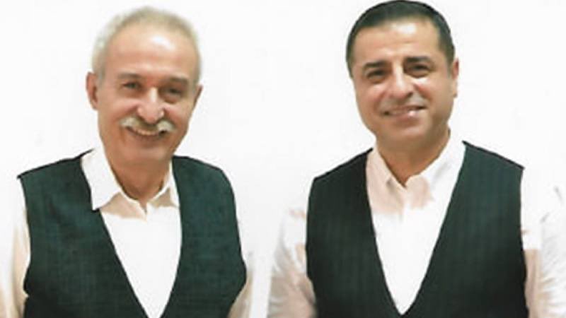 firarmond's tweet photo. Sakızcı Memo

Hapishanenin beton duvarına asılı iki karışlık televizyon açık. Selçuk Mızraklı ile masada oturuyoruz, Hoca’nın önünde her zamanki gibi bulmaca var. Gözlükleri, kırlaşmış saçı ve bıyığıyla Einstein’ı andırıyor. Atomu parçalamadı ama sabrıyla, iradesiyle yedi yılda beton duvarları “çatlattı”.

Bu defaki bulmaca bir hayli zor olsa gerek, Hoca içinden çıkmaya çalışıyor. Epey düşündükten sonra buluyor, soldan sağa dokuz harfli “kardeşlik”miş. “Sorusu neydi?” diyorum. “Sorusu cevabından daha zor.” diyor.

MGK kararıyla yürürlüğe gireceği zannedilen yıpratılmış, örselenmiş, içi boşaltılmış, kollektif duygu durumu.

“Zormuş.” diyorum.

Dr. Adnan Selçuk Mızraklı 63 yaşında, Diyarbakır’ın yüreği sevgiyle dolu genel cerrahı. Sadece dört ay belediye başkanlığı yapabildi. Sonrasında suçsuz, günahsız, delilsiz, hukuksuz yedi yıl hapis.

Hava çok sıcak, basık, boğucu, terliyoruz habire. Bazen bu kuyunun dibinde nefes almak bile zorlaşıyor. Hoca’nın gözü bir ara televizyona takılıyor, bir süre kalıyor öyle. Neye baktığına bakıyorum.

Dört ay belediye başkanlığı yapabilmiş suçsuz, günahsız, yüreği sevgiyle dolu Diyarbakır’ın doktoru, yedi yıldır tutulduğu hücreden, 25 yıl belediye başkanlığı yapmış Ankara’nın parsel parsel günah yüklü şahsiyetinin sakız çiğneyerek adliyeye girişini izliyor.

Bulmaca giderek zorlaşıyor ama Hoca inatçı, yukarıdan aşağıya altı harfli, “adalet”. Sorusu neymiş? “Geç olsa bile gelmeyen, MGK kararıyla gelebileceği zannedilen insan onurunun mütemmim cüzü.” Zormuş gerçekten.

Şahıs az sonra elini kolunu sallayarak adliyeden çıkıyor, “Ben öyle çekirge gibi üç defa değil, 500 defa sıçradım.” diyor. “Keramet sakızda mı acaba, sen bir defa bile sıçrayamadın Hoca.” diyorum. “Yok.” diyor, “O çiğnediği sakız değil, insanlık onuru. Ben bir defa bile çiğnemedim, çiğnetmedim de.”

Dr. Adnan Selçuk Mızraklı, Diyarbakır’ın dört ay belediye başkanlığına karşı yedi yıl hapis yatmış ve cezasını tamamlayarak, “kardeşlik” henüz ona uğramadan 8 Eylül Salı günü tahliye olacak temiz yürekli bilgesi.

Son beş yıldır ben ona emanettim, o bana emanetti. Salı sabahı buradan çıkacak, akşamına da Diyarbakır Havaalanında olacak. Artık size emanettir.

İçeriden dışarıya sekiz harfli. “ÖZGÜRLÜK”. Hoca bulmacayı tamamlamak üzere.

Televizyonun sesini kısıyoruz, şahıs halen bir şeyler söylüyor. Az sonra haberlerde sürecin geldiği aşamaya ilişkin ayrıntılar verilecekmiş.

Hoca, bulmacadaki son soruyu da çözüyor. Tepeden tırnağa beş harfli: “İRADE”. “Sorusu neymiş?” diyorum. “Bunun sorusu yok” diyor Hoca, “Sadece cevabı var.”

Hoca, Salı akşamı Diyarbakır’da havrılısıyla. Kesin.
Sakızcı Memo da karşılamaya gelir. Yalnız, bizim sakızcımız çok haysiyetlidir, başkalarıyla karıştırmayın sakın.

Tû her hebî Mamoste. Her bijî. Biçe rêya te her tim vekîrî be.

Selahattin Demirtaş
5 Eylül 2026