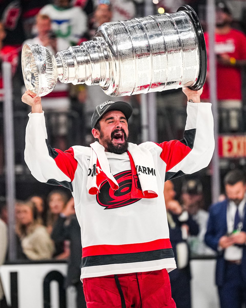 Photo of Seth Jarvis holding the Stanley Cup over his head during the postgame celebration after the Canes won the championship