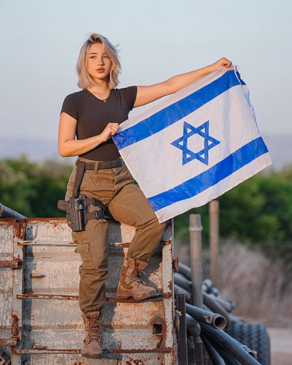 LiorAvraham08's tweet photo. Standing tall amid the ruins, she carries the weight of a nation’s resolve. In the dust and fire of war, her gaze pierces the horizon unyielding, unbreakable. https://t.co/qx6BT8Ewiv