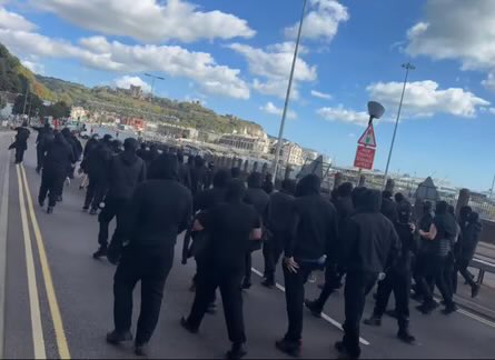 BootneckMajor's tweet photo. The Dover Protest: Observations

This being my neck of the woods, I thought I’d take a trip down to see what all the fuss is about.

In fact, I can’t get anywhere near the seafront because of the extensive road closures, so I’m having to rely largely on the imagery available online.

Several things stand out.

Firstly, the tactics.

Whatever the adequacy of the police intelligence beforehand, the protest itself appears to involve considerable planning. The logistics, coordination and timing look extremely well organised.

Then there is the demeanour of the protesters. Almost silent. Non-violent. Disciplined.

Their clothing is coordinated and remarkably uniform. I use the term “uniform” deliberately.

The near-universal face covering also frustrates identification and subsequent intelligence gathering. Whether that is its principal purpose or not, it is certainly the effect.

Most strikingly, there is a conspicuous absence of the nationalist imagery normally associated with protests of this kind. Few, if any, English flags. Instead, there is a preponderance of Christian symbolism.

This creates the impression of something framed less as a conventional “far-right” demonstration and more as a cultural and spiritual show of strength.

We should be careful about claiming to know precisely who is organising it, or what every participant believes. But we should be equally careful not to dismiss what is plainly being communicated.

These men are angry. Really, deeply angry. They appear disciplined, organised and intent on demonstrating both their frustration and their strength.

Whatever one thinks of them, that is the significant point. This does not look spontaneous, chaotic or unserious.

It looks deliberate.

And it would be foolish not to ask what comes next.