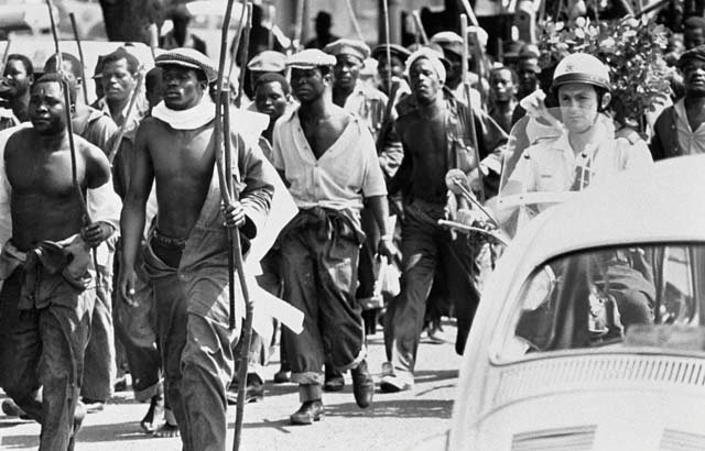 HistorySAZAR's tweet photo. Strikers march through central Durban escorted by traffic policeman, c 1970s, South Africa. Credit: David Hemson Collection / UCT Photography Collection https://t.co/NdLKqBzG3Y