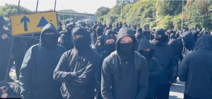 AjaTheEmpress's tweet photo. I do feel the need to point out that these are all the same picture:

1) Men in Dover today
2) Muslim men
3) Trans rights activists
4) Antifa

Some people only seem to have noticed or cared about No. 1.

I don't like any of it, regardless of who's doing it or what label is attached to them.

It is intimidating AF when you're on the wrong side of a group like this, and sadly, like many other women, I have experienced that from groups 3 and 4.

The standard should be the same for everyone. No face covering allowed.