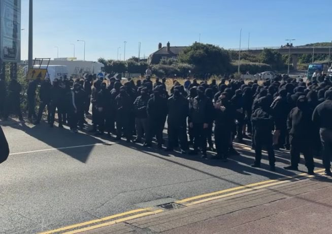 YourAnonCentral's tweet photo. A Russian &amp; Israeli-funded disruption operation sees black-clad right-wing thugs in balaclavas block UK’s largest international ferry port, which handles roughly one-third of UK–EU trade. An estimated £16.4 million worth of trade per hour. Promoted by IDF linked Tommy Robinson. https://t.co/uZUiVNHbTs