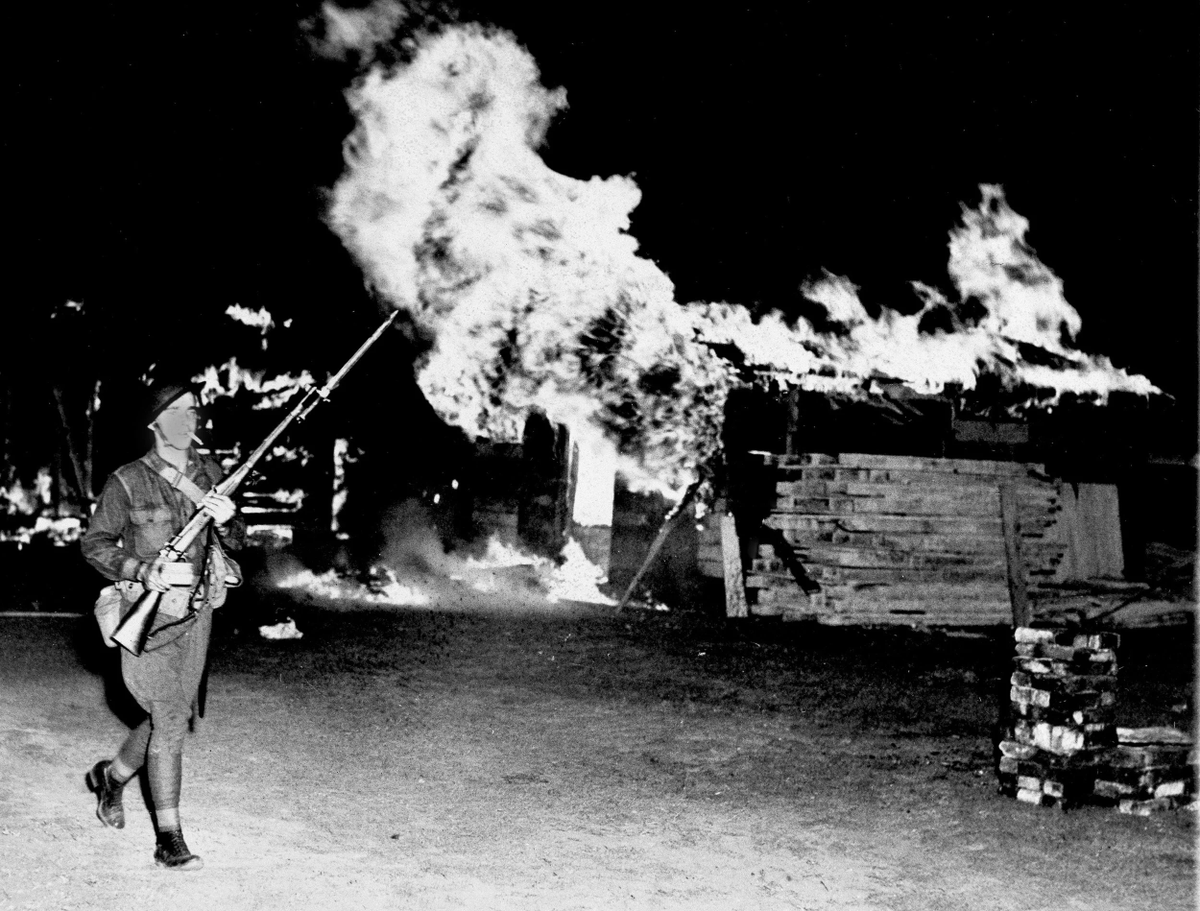 EchoesofWarYT's tweet photo. A federal soldier passes by burning shacks that fleeing Bonus March veterans abandoned, at Camp Marks, on the Anacostia Flats in Washington, D.C., July 29, 1932. This was the fourth veterans' camp to be burned. https://t.co/mOqS6dFP2v